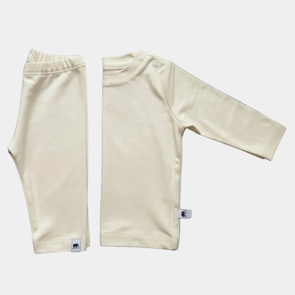 A two-piece baby clothing set in a warm cream/off-white color, consisting of a long-sleeve top with shoulder buttons and matching pants, laid flat on a white background.
