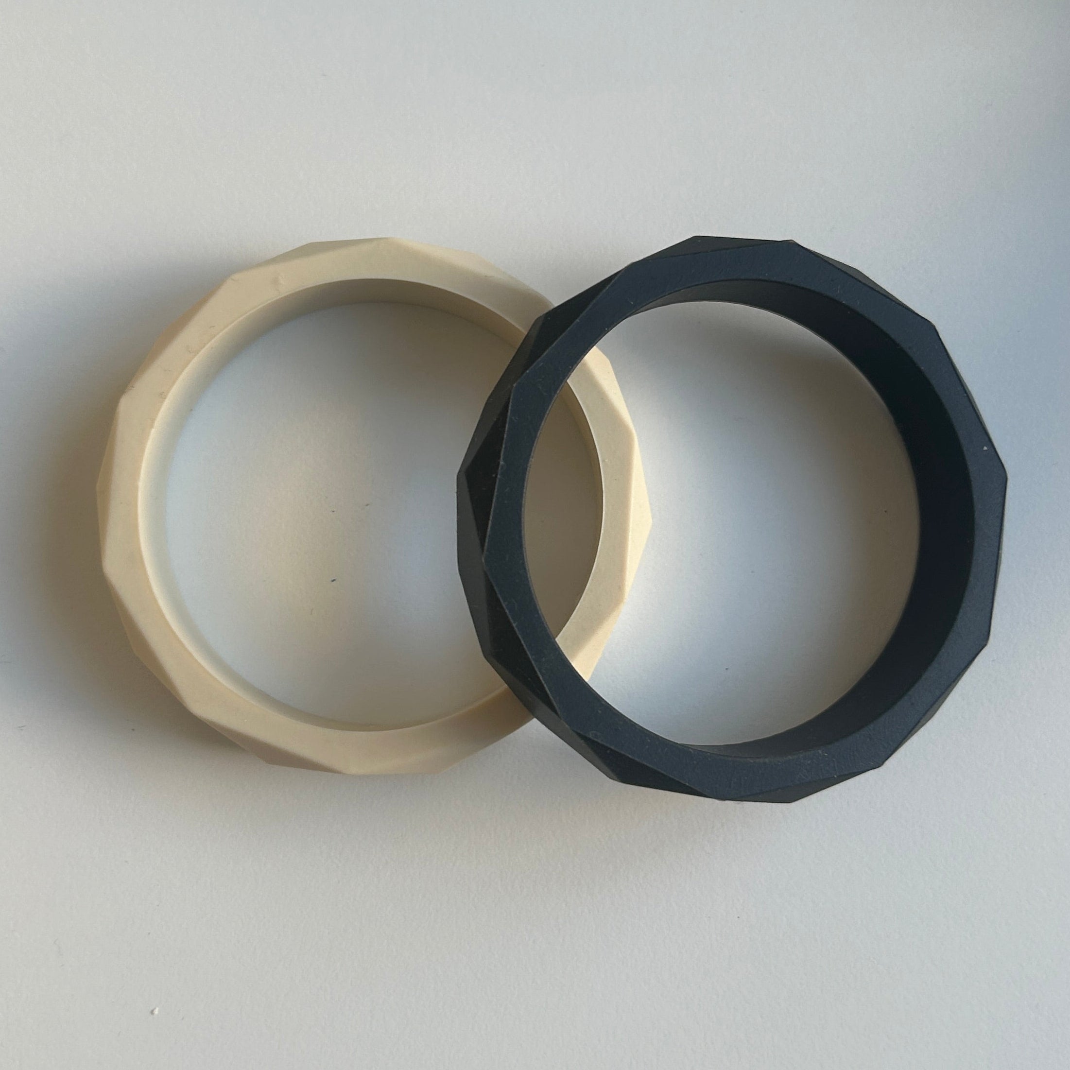 Two black and beige silicone bracelets on a light gray background