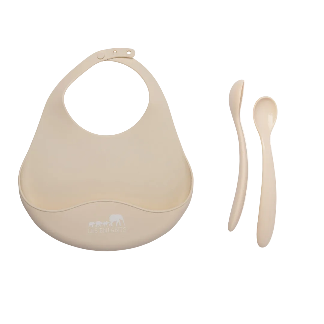 Beige baby bib and spoon set on a white background